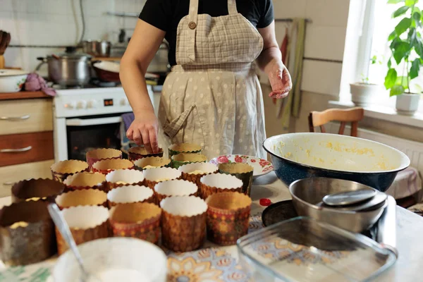 Bir kadın aşçı paskalya pastası pişirmek için kağıt kalıplarda şekerli meyvelerle hamur döker. Aile gelenekleri ve tarifleri. Küçük aile işletmesi ve sipariş edilecek hamur işleri ve tatlıların hazırlanması.