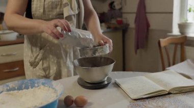 Fırın konseptine yakın çekim. Kadın pişirmek için metalik elek ile kakao tozu karıştırıyor. Ev yapımı yemek.