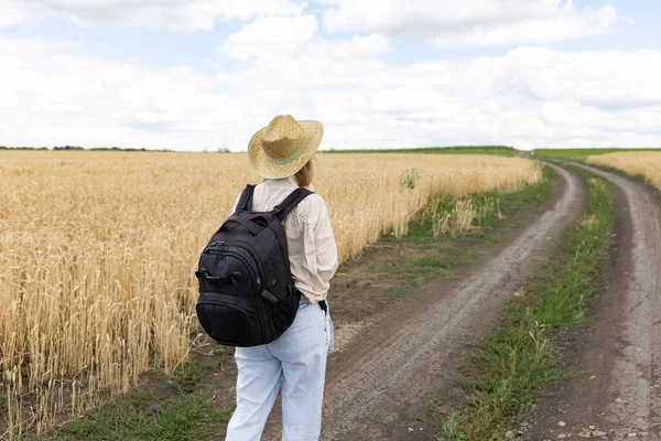 Žena Turistka Klobouku Batohem Kráčející Cestě Kolem Pšeničného Pole Pohled — Stock fotografie