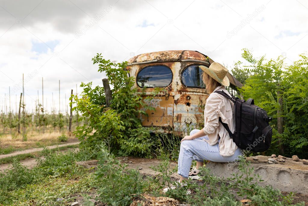 Woman sitting next to old abandonedrusty bus in Ukraine