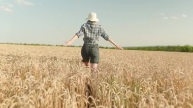 Woman runing fun across the wheat field. agriculture dream concept. girl farmer hands to sides runs across the wheat field. happy free girl run in park agricultural land
