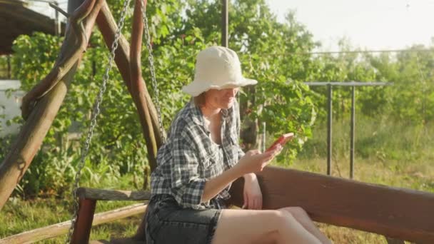 Woman Looks Smartphone Swinging Swing Garden Rest Hard Day — Stockvideo