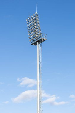 Gökyüzü arka planında spor stadyumunun ışıklandırma sistemi. Bir futbol stadyumunun ışıkları kullanılmıyor. Stadyumdaki gece sporu etkinliğini aydınlatacak bir sürü parlak projektörü olan ışık kulesi..