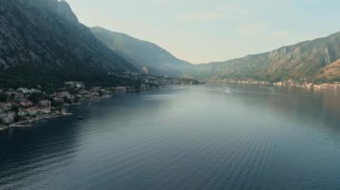 Montenegro. Adriatic Sea. Bay of Kotor. Popular tourist spot. Village on the coast. Houses with orange tiled roofs. Summer. Tourist season. Drone. Fly. Aerial view. The camera moves from left to right