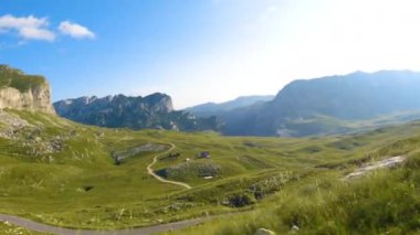 Karadağ. Durmitor Ulusal Parkı. Eyer Geçidi. Alp çayırları. Dağ manzarası. Çekimler yolda geçen bir arabadan yapılıyor.