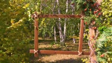 Sonbaharın başında. Yaprak döken orman. Ağaç dalına asılı ahşap bir çerçeve. Hiç kimse. Yakın plan.