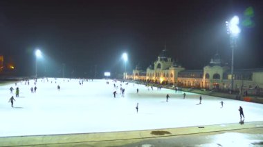 Macaristan. Budapeşte şehri. Kış akşamı. Caddedeki buz pateni pistinin panoraması. İnsanlar paten kayıyor. Sabit Kamera