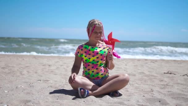 Dziewczyna Różowymi Afrykańskimi Warkoczami Siedzi Pustej Piaszczystej Plaży Trzyma Rękach — Wideo stockowe