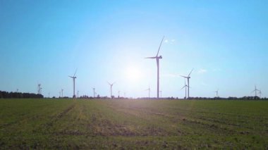 Mavi gökyüzüne karşı bir tarlada çalışan bir rüzgar çiftliği. Yeşil enerji. Güneşli bir gün. Sabit Kamera