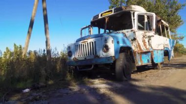 Ukrayna 'da savaş. 2022 Rus istilası Ukrayna. Sivil halkın terörü. Savaş suçu. Kırsal kesimde. Bombardımandan sonra otobüs hasar gördü. Panorama. Kamera soldan sağa hareket ediyor.