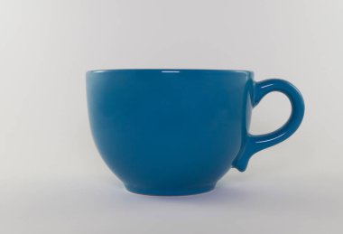 Beyaz arka planda tek kulplu boş mavi bardak. Çay, kahve, süt ya da su içmek için. Yakın plan.