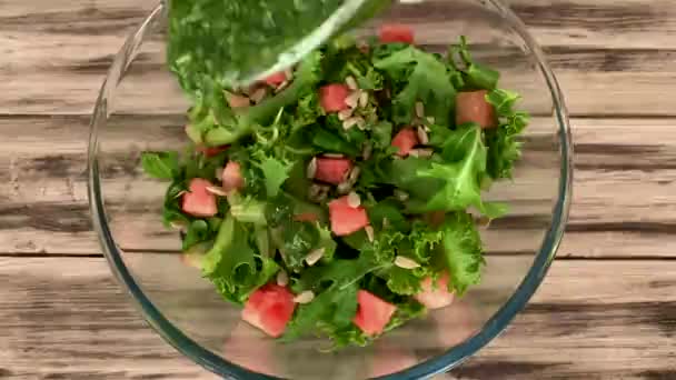 Pesto sauce hældes på en salat med vandmelon og solsikkefrø. – Stock-video
