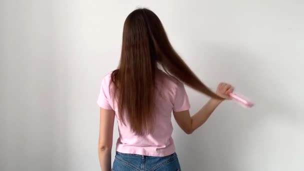 Μια γυναίκα με μακριά μαλλιά χτενίζει τα μαλλιά της και φροντίζει τα μαλλιά της. — Αρχείο Βίντεο