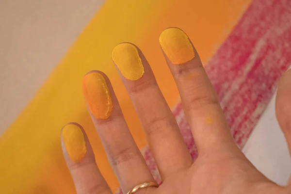 Mãos manchadas com lápis de cor pastel. Uma mulher pintora desenha um quadro laranja. — Fotografia de Stock