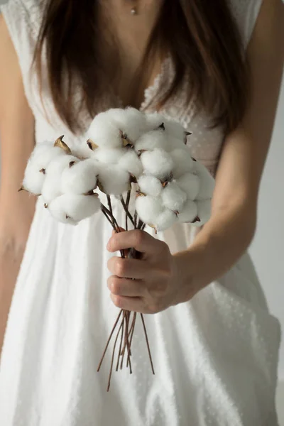 Donna in un abito tiene in mano un mazzo di ramoscelli naturali con fiori di cotone. — Foto Stock