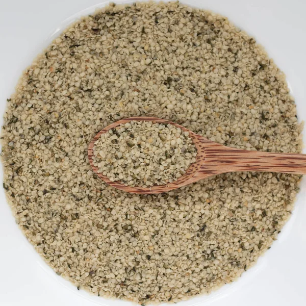 Çember şeklinde bir tohum arka planında tahta kaşıkta kenevir tohumları, fotokopi alanı ile üst görünüm — Stok fotoğraf