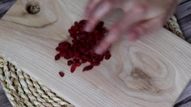 Bir kadın eli, tahta bir tahtanın üzerinde Goji Berry 'leri Kalp şeklinde düzenler..