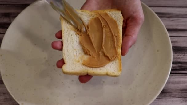 女性の手はトーストのスライスにピーナッツバターをスミア — ストック動画