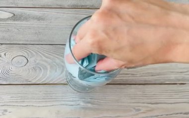 Bardaktaki mavi yapışkanlı kağıtlar. El, bardaktan kağıt çarşafları çıkarır..
