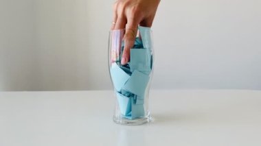 El, bardaktaki mavi etiketleri alıp etrafa saçıyor..