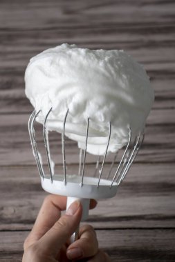Ahşap arka planda çırpılmış çırpılmış yumurta beyazı. Dikey resim