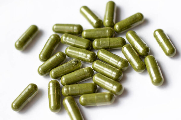 Green capsules on a white background.