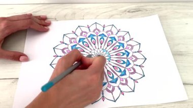 Bir kadın mandalayı kalemle çizer ve boyar. Çizim yoluyla stres atma eğilimi. Sanat terapisi