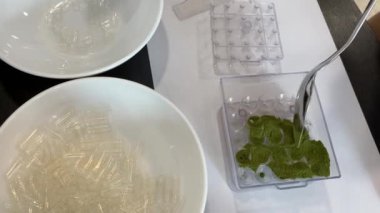 Filling the empty capsules in the capsulizer PART 2. Pouring the green vitgrass powder into the empty tablets