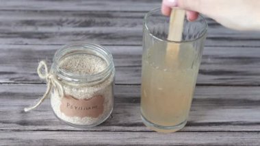 Psilyum, psyllium kabuğudur. Bir el, bir bardak sıcak suda psyllium karıştırır.