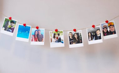 Lots of photos of a couple in love hanging on a rope on the wall with clothespins of hearts. Instant Polaroid photos clipart