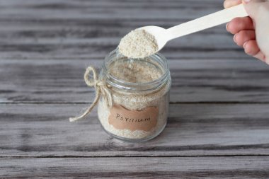 Psyllium etiketli bir kavanozda muz kabuğu ve ahşap arka planda bir bardak su.