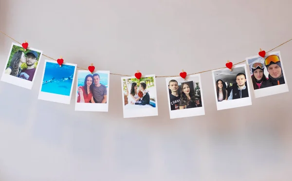 Lots of photos of a couple in love hanging on a rope on the wall with clothespins of hearts. Instant Polaroid photos