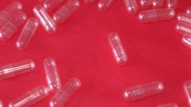 An empty capsule rotates on a red background