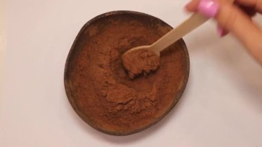 Carob powder in a coke bowl. Picks up a spoonful of carob for a hot drink