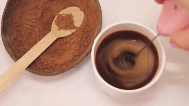 Carob is a hot drink. Stirring the carob powder with a cappuccinator in a cup