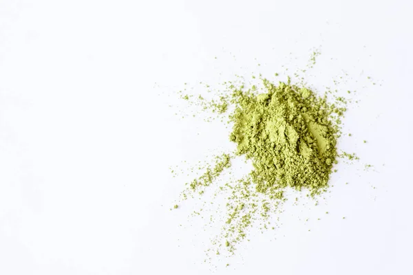 Matcha green tea powder on a white sheet of paper. Explosion on white background on top. Scattered matcha with a copy of space.