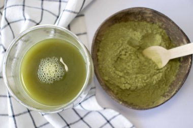 Matcha green tea in a cup with a bowl of powder. Flat view from above
