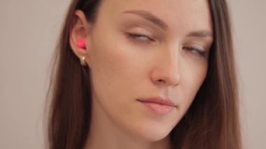 A young brunette woman takes earplugs out of her ear. Noise protection