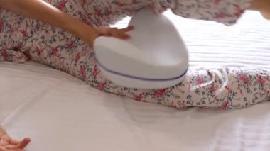 Orthopedic foot pillow for knees. A young woman puts a pillow with memory effect to sleep comfortably. Pillow with memory effect between the legs. Pillow for sleeping.