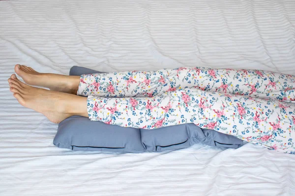 Woman's legs lay down on a pillow for relaxing and preventing varicose vein.