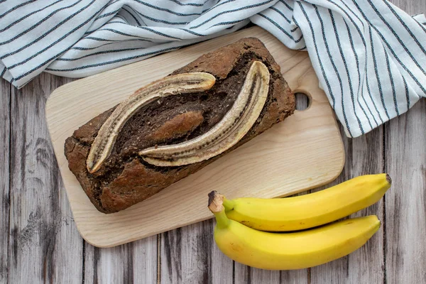 Crunchy cinnamon banana bread on a wooden background with a napkin and fresh ripe bananas. A sugar free and gluten free meal