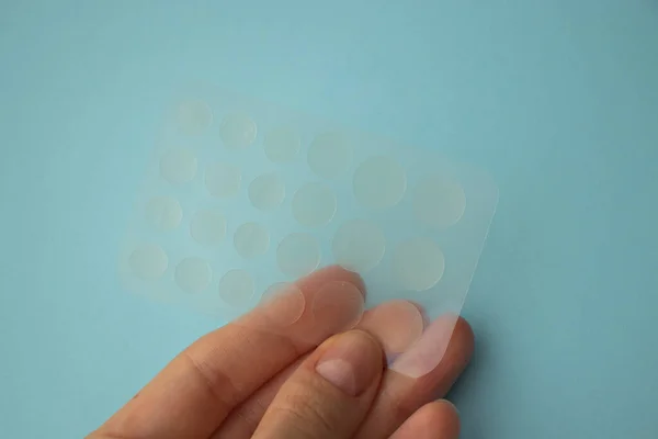 Acne treatment anti-cellulite patch for acne in a womans hand on a blue background