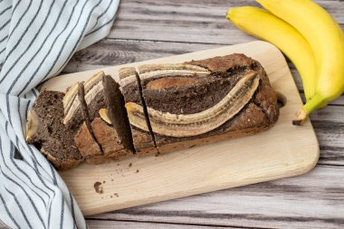 Taze muz ve çizgili bir mutfak havlusuyla dilimlenmiş muzlu ekmek.