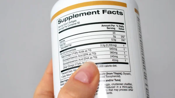 IRPEN, UKRAINE, 23 AĞUSTOS 20222, Bir kavanoz balık yağı ilavesi üzerine kadın kompozisyonu okuyor, Omega 3, İllüstrasyon Editörü