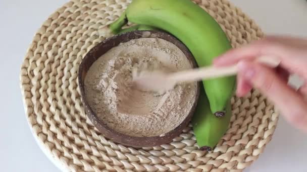 Ronde Kokosnootplaat Met Bananenmeel Lepel Rauwe Bananen Een Houten Ondergrond — Stockvideo