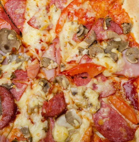Piece of pizza close-up. Pizza with bacon, ham, mushrooms, tomatoes and cheese.