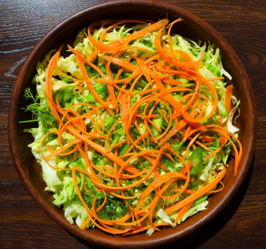 Taze sebze salatası. Havuç, taze lahana, yeşil pırasa ve dereotu masada seramik tabakta..