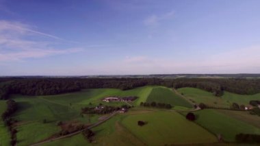 Yuvarlanan tepelerin üzerinde insansız hava aracı, arka planda doğal çitleri, çiftlikleri, kırsal yolları ve ormanları olan otlaklar, Güney Limburg 'da üç ülkeden oluşan Belçika sınırına yakın olan Hollanda sınırı. Hava Görüntüsü Kıvrımlı Yaz mevsimi Altın Saati
