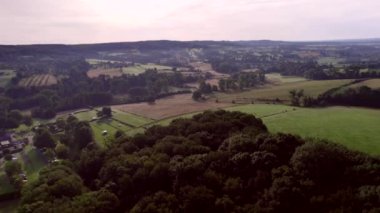Drone Forwards hafif kıvrımlı kamp alanları, yuvarlanan tepeler, doğal çitleri olan çitler ormanlık alanlar, tarlalar, kırsal yollar ve orman arka planda, Güney Limburg, Hollanda. Hava manzaralı altın saat yaz sezonu