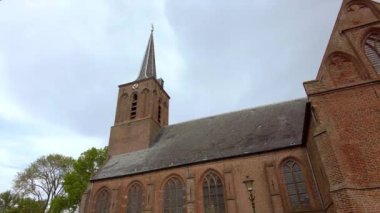 14. yüzyıldan kalma manzaralı bir koridor boyunca alçak açılı bir manzara. Daha az kilise, Hollanda 'da Schellinkhout' ta küçük bir köyde güzel Gotik vitray pencereli bir kilise kulesi.